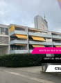 Multi-story commercial or residential building with yellow awnings and balconies, located on Route du Silo 26-36 in Renens. The building has a depot on the ground floor.