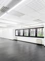 empty room, white walls, black tile floor, white suspended ceiling, large windows, radiators