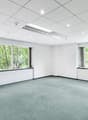 empty room with white walls, white ceiling, carpeted floor, three large windows with a view of trees outside
