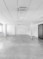 empty room, white walls, gray flooring, large windows, two doors