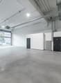 Empty parking garage, concrete flooring, white walls, double doors, and a large entrance