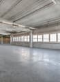spacious room, concrete floor, high ceiling, large windows, metallic beams