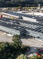 industrial building with solar panels, parking lot, and surrounded by greenery
