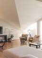 Living room with large glass window, balcony, wooden floor, large sofa, coffee tables, armchairs, television