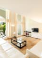 Leather couch, glass coffee table, television, red cabinet, mirror, wooden floor, white walls, picture frames, white curtains, balcony, outdoor furniture