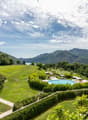 overlooking a wide green landscape with a swimming pool and mountains in the background