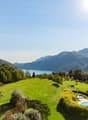 vast grass field, swimming pool, trees, lake view, clear sky