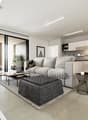 Spacious open-plan living room with large windows, grey sofa, coffee table, and modern kitchen area with white cabinets and concrete countertops. The room has a minimalist and contemporary design with a balcony or terrace visible through the windows.