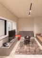 modern living room with beige walls, large windows, beige couch, TV, coffee table, rug, telephone