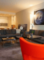 modern living room, with gray sofa, orange chair, glass tables, and flower vases