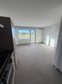 tiled floor, large glass window, white walls, ceiling lamp, kitchen area with black countertop
