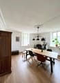 long dining table, white wooden bench, modern chairs, vintage cabinet, white walls, picture frames, ceiling lamp, large windows, wooden floor