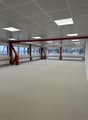 large open space, white carpet, multiple large windows, exposed steel beams