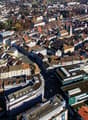 Aerial view of a densely populated city with many multi-story buildings, rooftops, and a mix of residential and commercial structures. The city appears to be a historic European urban center with a compact layout and narrow streets.