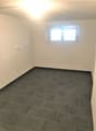 Empty room with white walls, grey tiled floor, one window.