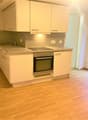 modern kitchen with white cabinetry, wooden floors, built-in oven, stainless steel sink, tiled countertop