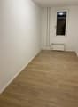 Empty room with wooden floors, white walls, an exit door with a glass panel, and an electrical outlet.