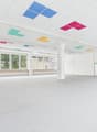 spacious room, white walls, ceiling with multicolored square panels, large windows, carpeted floor