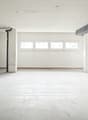 Empty room with a concrete floor, white walls, a pipe on the wall, and multiple windows