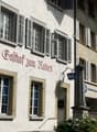 Facade of a building with multiple windows, a lamp, and a sign reading 'Balthof zum Raben'.