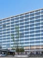 modern office building, multiple floors, glass windows, car parked in front