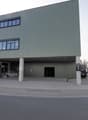 modern commercial building, steel and concrete, green facade, large glass windows, main entrance with glass doors, signage