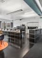 modern interior design with white walls, large windows, black flooring, grey carpeting, modern seating, long tables, built-in cabinets, office equipment