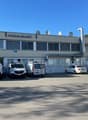 Office building with multiple windows, cars parked in front, satellite dishes on the roof
