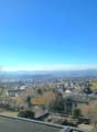 top view of a neighborhood with houses, mountains, and wide valley, rooftops, trees and a road in between