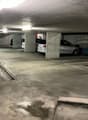Underground parking garage with concrete walls and floor, several parked cars visible