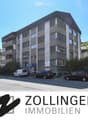 3-story building, grey concrete, multiple windows, parking spaces in front