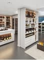 Large, well-lit wine store with extensive shelving and display of wine bottles and glasses. Central display island with additional wine storage. Large windows provide natural light. Variety of wine types and brands available for purchase.