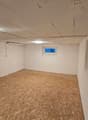 unfinished room with white walls, unfinished ceiling with cracks, small window, unfinished floor with plywood