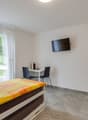 bedroom with bed, desk, chairs, television, curtains, tiled floor