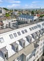 multiple story building with a terrace, windows, chimneys, a sloped roof, balconies, and city view