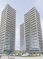 Skyscraper building, two tall buildings, concrete exterior, many windows, car park in front, street, trees, other buildings