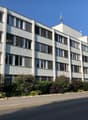 4 story apartment building, white walls, multiple windows, shrubs in front