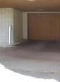 Garage space with a wooden door, brick floor, and parked car.