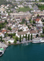 View of the town with many houses, buildings, a fountain, and a lake with boats