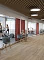 A gym with treadmills, weight machines, and people exercising or sitting on chairs.