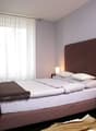 double bed, brown headboard, white curtains, white walls, bedspread, pillows, blanket, nightstands, lamps, rug