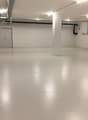 Empty room with white walls and floor, two doors, and pipes on the ceiling
