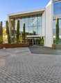 modern office building with glass walls, glass entrance, wide concrete brick courtyard, trees