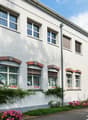 Two story white house with brick detail, multiple windows, bicycles parked in front.