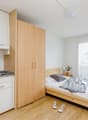 small kitchen area with appliances and utensils, wooden bed, wooden flooring, double window, sink