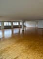 Large open space with hardwood flooring, multiple windows, and white walls. The room appears to be empty and suitable for various purposes such as an office, studio, or event space.