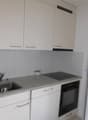White cabinets, granite countertop, sink, oven, dishwasher, trash bin, window with grills