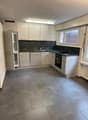 kitchen with white cabinets, granite countertops, stainless steel appliances, tile flooring, large window with daylight