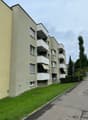 Multi-family house, balconies, multiple floors, grey exterior, green grass, sidewalk