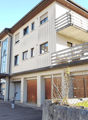 3-story apartment building with a balcony, garage, and fenced outdoor area
